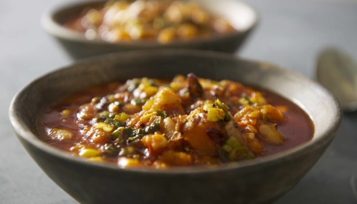 Vegetarian Locro in a bowl. It contains corn, different grilled vegetables and pumpkin soup. 